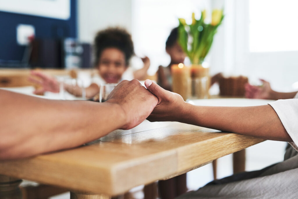 Family holding hands around a dining table