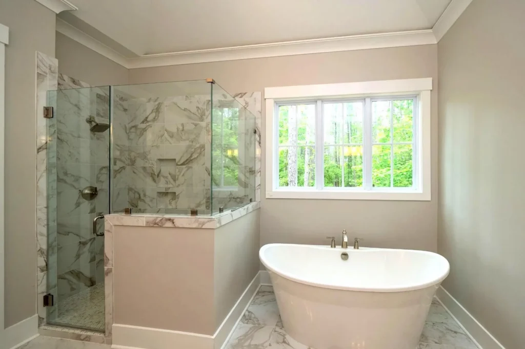 Freestanding bathtub beside a tiled shower and a large window
