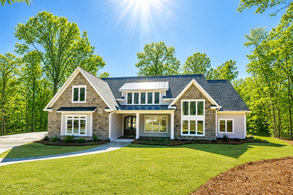 Home exterior with a central covered porch, multiple gables and a wide lawn